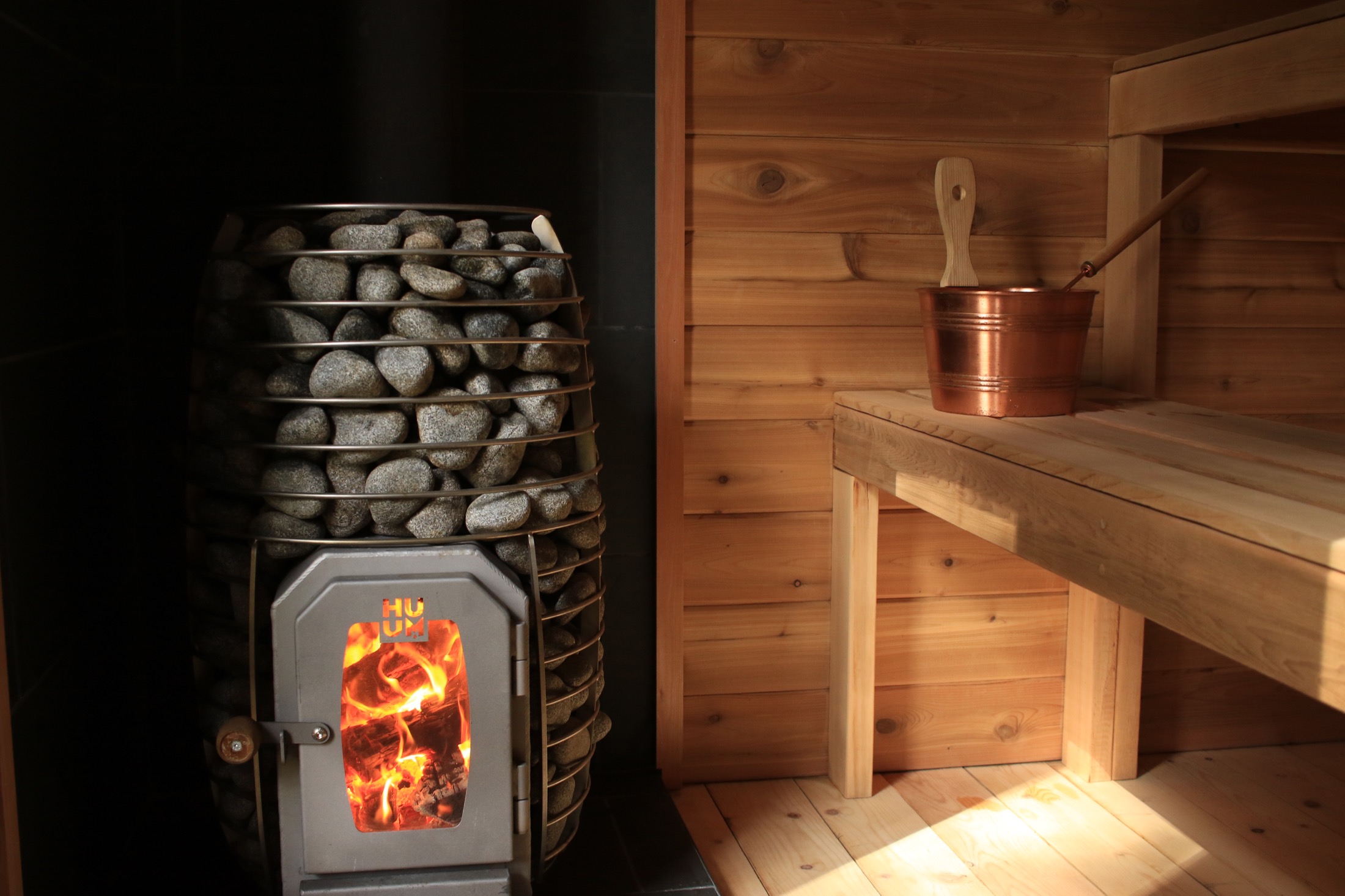 Wood-fired sauna heater, cedar benches, and bathing bucket